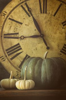 Still life of pumpkins and old clock in background