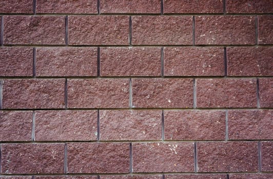 The wall of the large cherry-colored rectangular stones as background                               