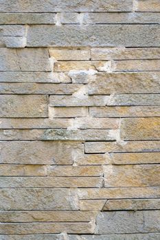 A fence made of beige narrow stones fastened by cement as background