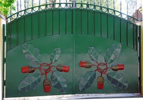 Green metal gate with forged pattern in the form of acorns                     