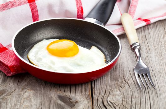 Fried egg in a frying pan, on an old wooden table