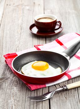 Fried egg in a frying pan, on an old wooden table