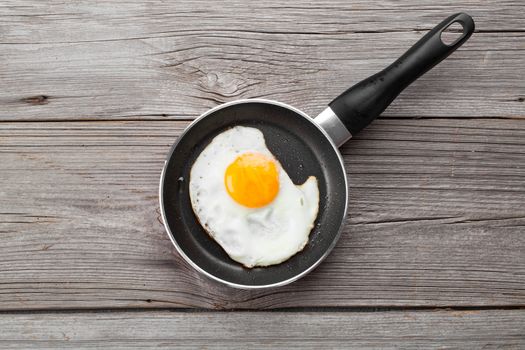 Fried egg in a frying pan, on an old wooden table