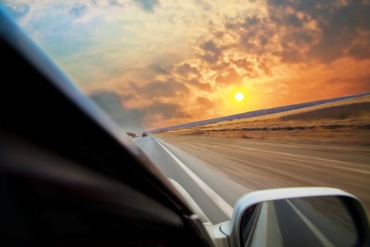 car moves on road towards to sunset