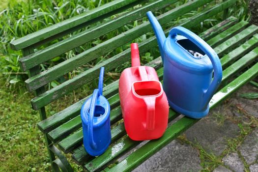 Watering cans in garden on bench against grass
