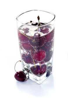 Sweet cherry in vials in glass with water on white background