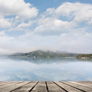 Lake with mist and cloud, focus on wooden desk table.