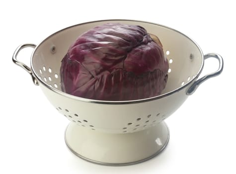 Red cabbage in the white enamel colander on the white background