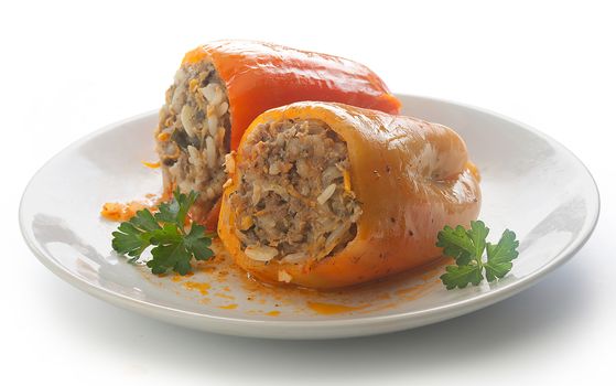 Two stuffed peppers with fresh parsley on the white plate