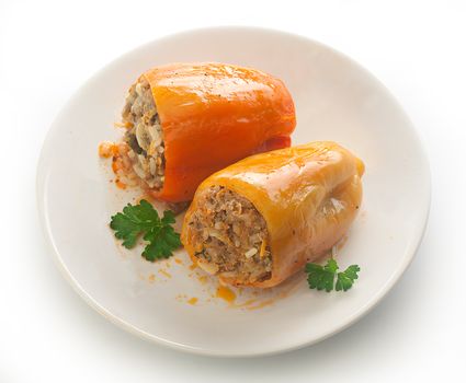 Two stuffed peppers with fresh parsley on the white plate