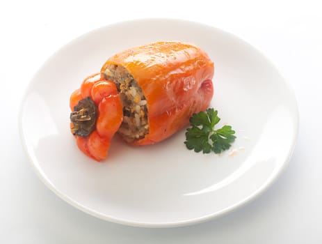 One stuffed red pepper with fresh parsley on the white plate