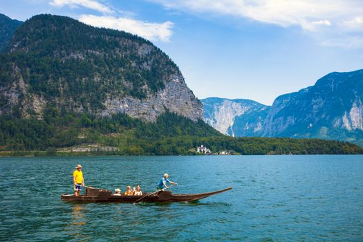 Hallstatt, Austria - August 7, 2013: People crossing the lake with a traditional boat typical for Hallstatt village, Austria