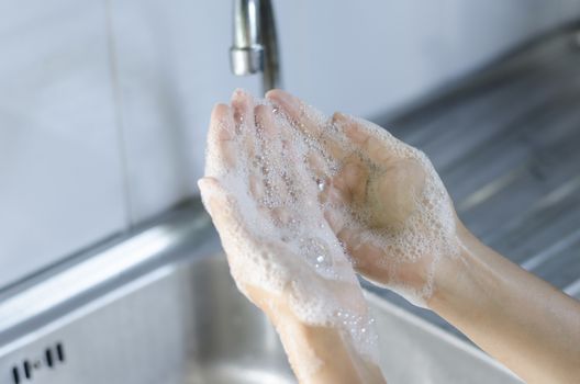 Washing of hands with soap on sink