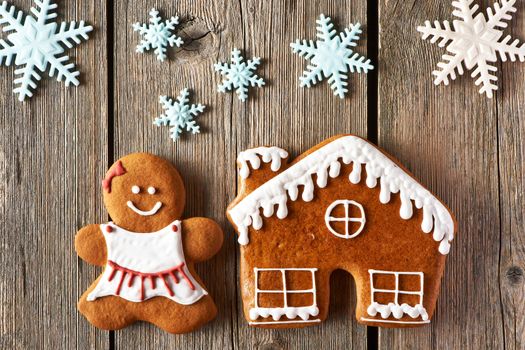 Christmas homemade gingerbread girl and house on wooden table