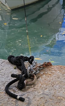 A close up of ropes and chains used to moor a boat in a harbour