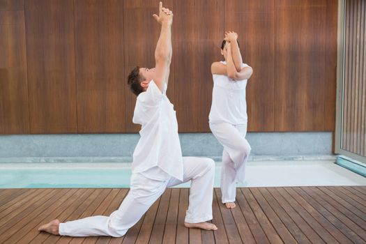 Peaceful couple in white doing yoga together in health spa