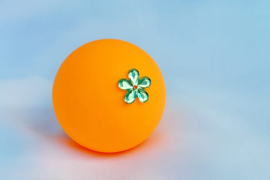 The orange ball decorate by plastic flower.Invent it be a toy for children.