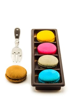 Colorful macaroons with fork on white background