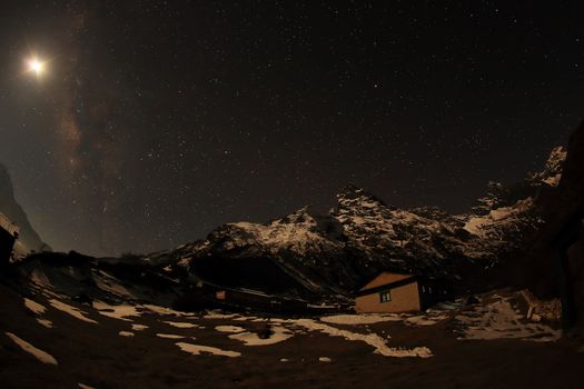 Night sky with clouds and stars passing by behind mountain Khumbila, Dole village. Nepal