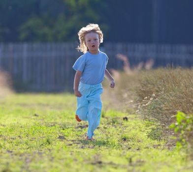 boy with long blond hair running toward the camera