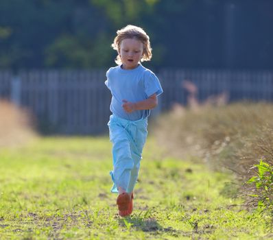 boy with long blond hair running toward the camera