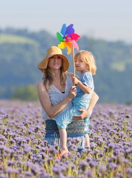portrait of mother and son playing with pinwheel in a field