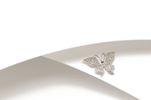 Elegant silver diamante butterfly ornament or brooch with outspread wings displayed on a two-tone silver and white background with copyspace