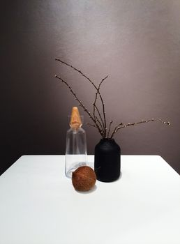 Vase with tree branches and decorative objects on the table.