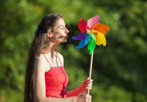 woman with long hair holding a multicolored pinwheel in a park