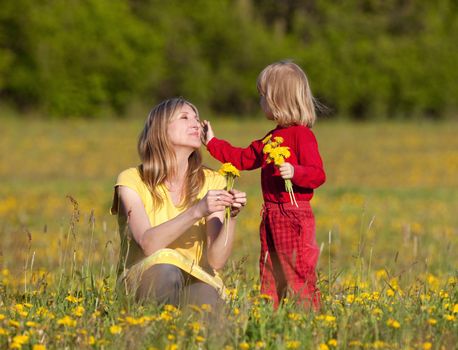 mother and son picking flowers at dandelion field in spring