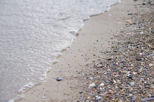 Photo shows a detail of the various stones on the sandy beach.