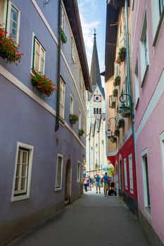 Hallstatt, Austria - August 7, 2013: Typical street with tourists in front of the Halstatt village church, Halstatt, Austria