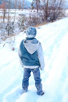 Young boy outside in the snow wearing blue