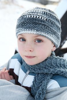 Young boy outside in the snow wearing blue