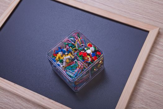 Colour stationery on black board in transparent box