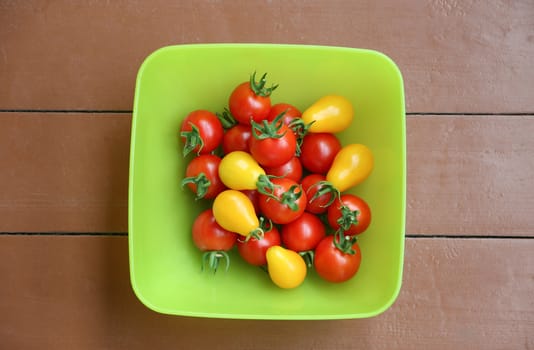 Red and yellow tomatoes in dish on wooden table