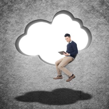 Cloud concept with man sit at a cloud shaped wall and using tablet.