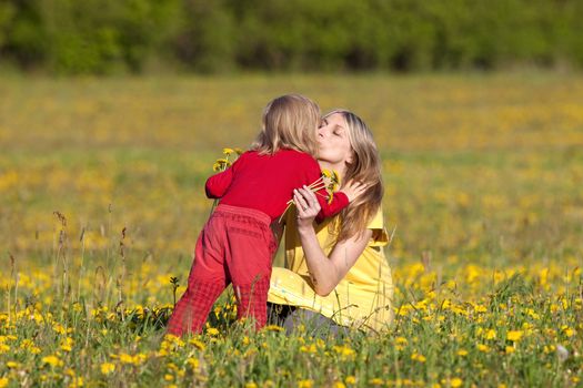 mother and son picking flowers at dandelion field in spring