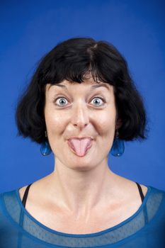 middle-aged woman sticking out her tongue - isolated on blue
