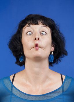 middle-aged woman making funny faces - isolated on blue