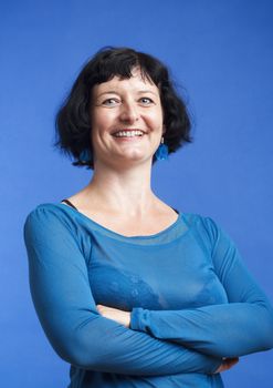 portrait of middle-aged woman with dark hair smiling - isolated on blue