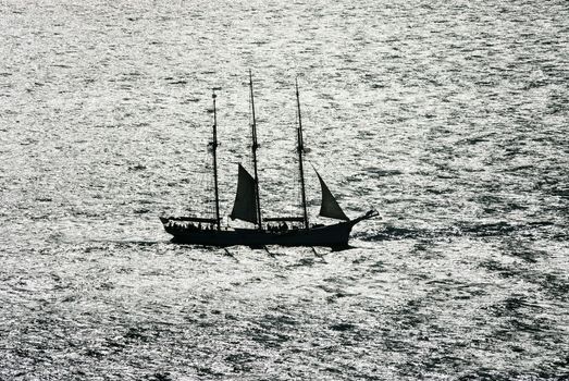 Sail boat gliding in open sea at sunset 