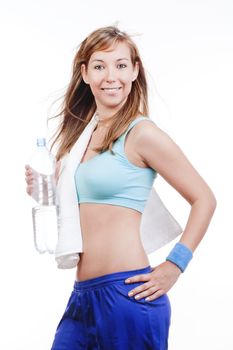 young woman in sports outfit holding a bottle of water smiling - isolated on white