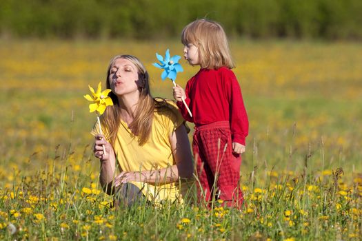 mother and son playing with pinwheels in a dandelion field