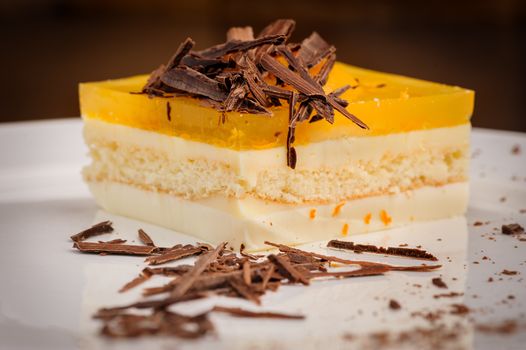 Layered delicious cheesecake with milk and orange jelly on plate