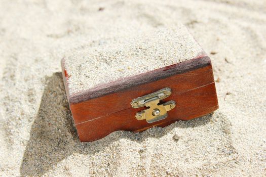 A closed wooden treasure trunk buried in a desert. Can be used for treasure, luck, suspense, and excavation concepts.
