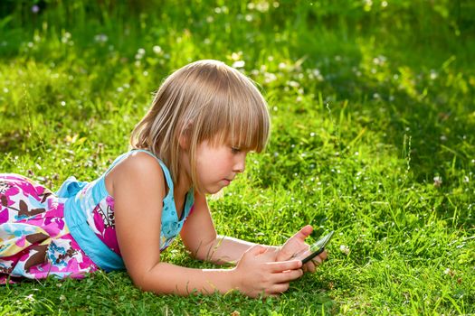 Little girl usng a touch pad in a summer garden