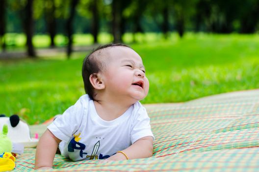 Asian baby sitting in park.