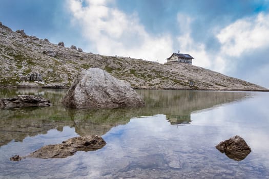 Italian Alps in Val Badia, Reflection of a mountain shelter in a lake