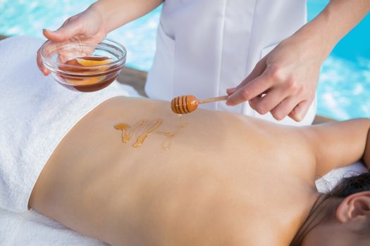 Woman getting a honey beauty treatment poolside outside at the spa